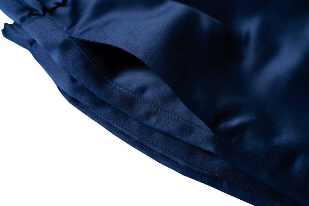 Fotografia commerciale 16 Tasca laterale del pantalone in raso blu di Juri Carissimi, con i riflessi del tessuto