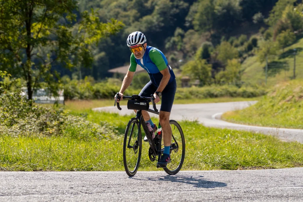 Fotografo moto sui passi in Lombardia 3 Ciclista in maglia verde e blu su bici da corsa sui tornanti di Polaveno (BS), 13 settembre 2026