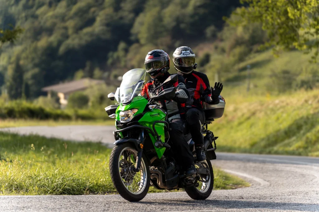Fotografo moto sui passi in Lombardia 15 Coppia su Kawasaki Versys-X 300 verde a Polaveno (BS), il passeggero saluta, 13 settembre 2026