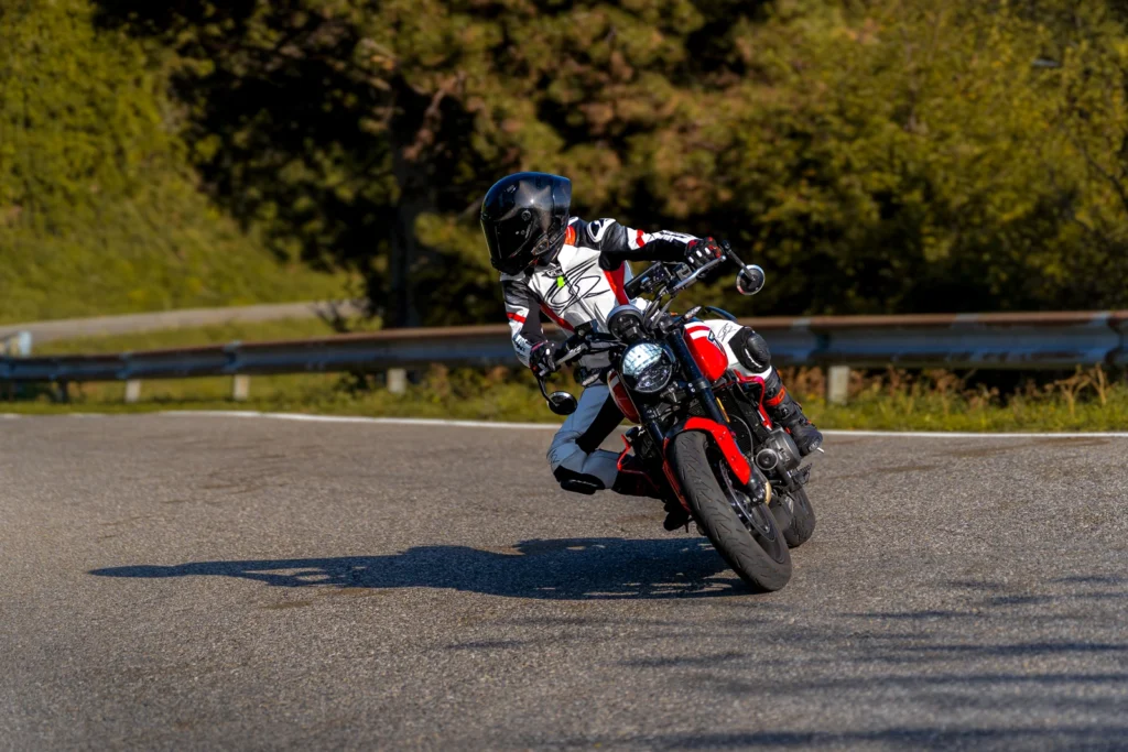 Fotografo moto sui passi in Lombardia 6 Motociclista in tuta bianca e rossa su Triumph Trident in piega ai Colli di San Fermo (BG), 3 ottobre 2026